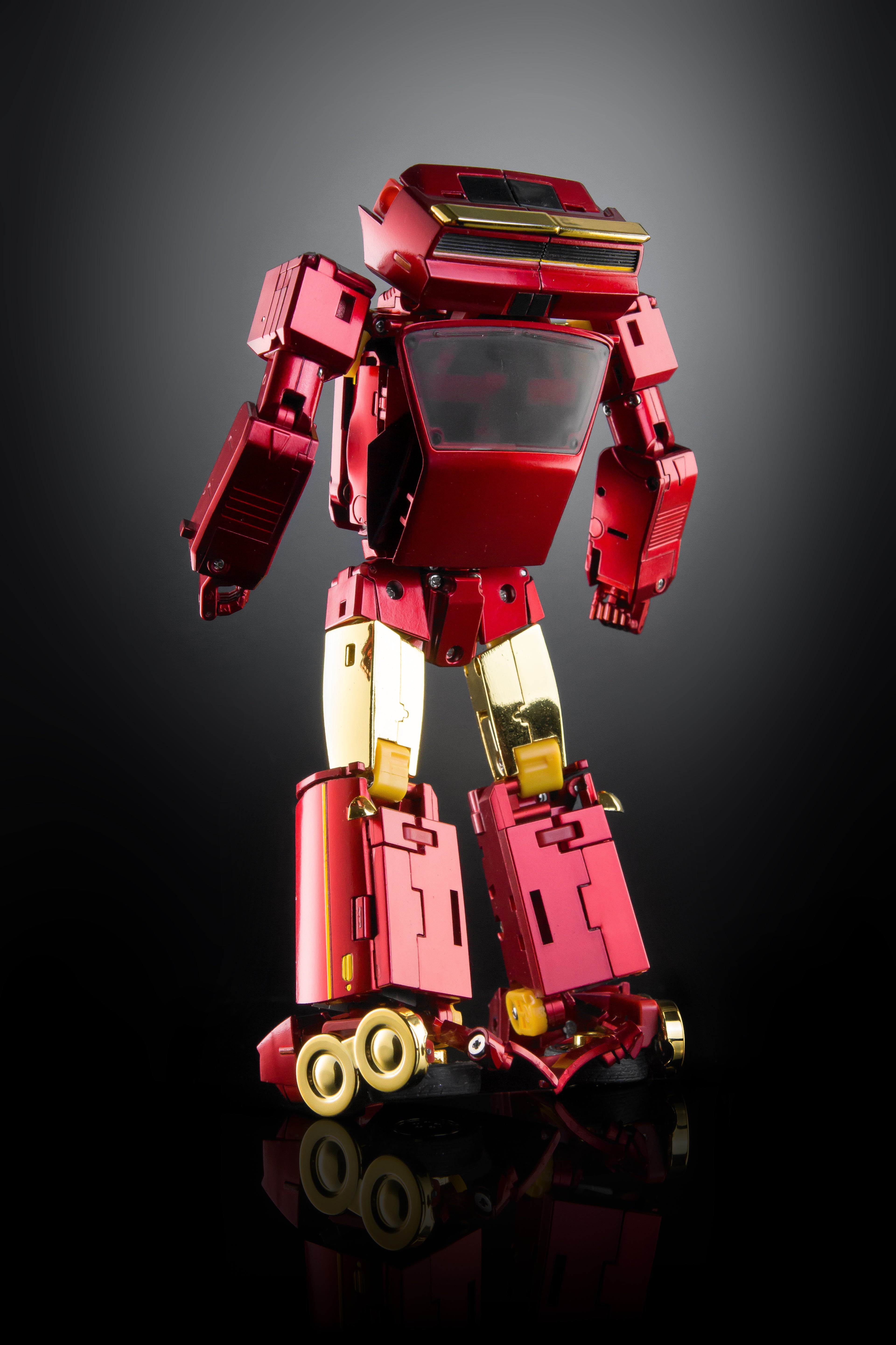 A metallic red and gold robot toy figure standing on a reflective black surface against a dark gray gradient background.